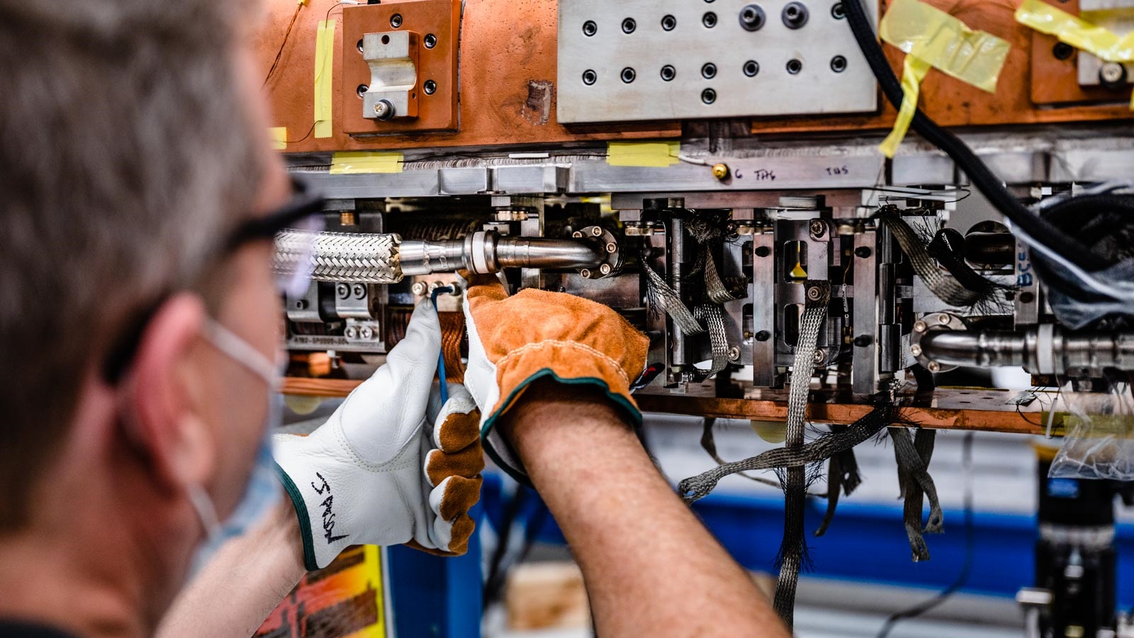 View from behind, man's arms and gloved hands working on equipment. (Image by Jason Creps/Argonne National Laboratory.)
