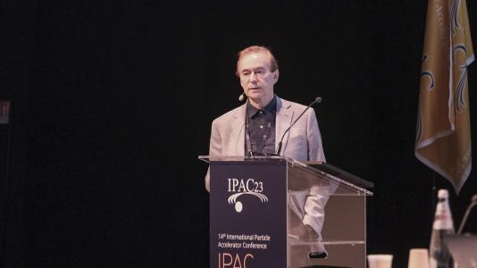 Alexander Zholents standing at a podium labeled IPAC23.