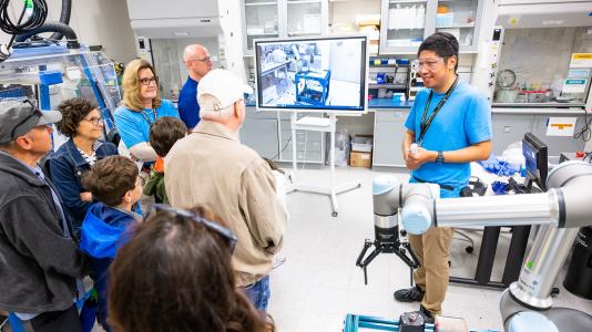 Adults and children listen to a presentation in a science lab during Argonne National Laboratory's Open House. 