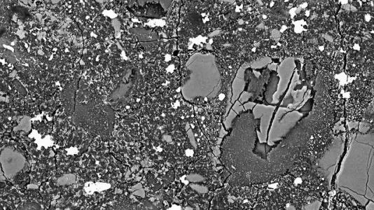 A team of scientists clarified the definition of the Earth's most abundant mineral – a high-density form of magnesium iron silicate, now called Bridgmanite – using Argonne National Laboratory's Advanced Photon Source. Above: Scanning electron microscope image of a bridgmanite-akimotoite aggregate. The backscatter electron image reveals an aggregate of submicrometer-sized crystals of bridgmanite and akimotoite enclosed in (Mg,Fe)SiO3 glass and within a Tenham shock-melt vein. Image credit: Tschauner et et al