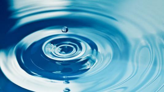 Water droplet rippling in blue water. (Image by Shutterstock / Peter Bocklandt.)