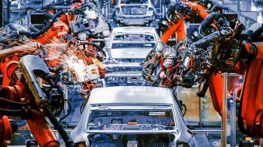 Line of cars being worked on by robotic arms. (Image by Shutterstock/Jensen.) 