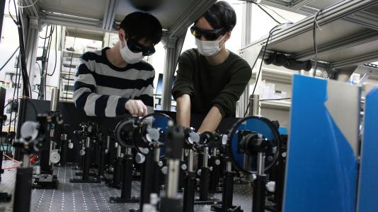 Photo of two men working on equipment. (Image by Tohoku University.)