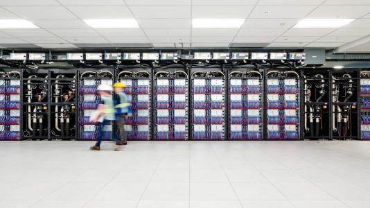 Two workers walking by a wall of the supercomputer. (Image by Argonne National Laboratory.)