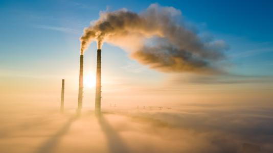 Smokestacks on horizon, spewing clouds. (Image by Shutterstock/Bilanol.)