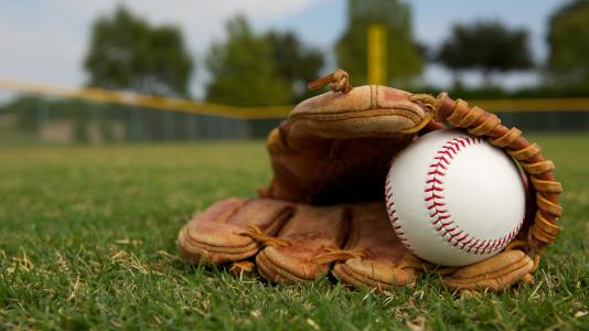 A baseball inside a baseball mitt in a field.