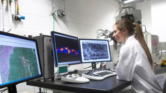 Woman scientist viewing electron microscopy images on computer screens