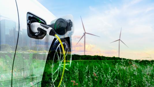 Composite image of an electric vehicle, city landscape, and field with wind turbines