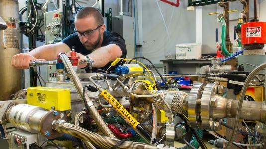 Argonne researcher Jim Sevik tightens the fuel rail on a natural gas direct-injection system at the lab. The engine is an automotive size single-cylinder research engine that operates with gasoline as well as natural gas.