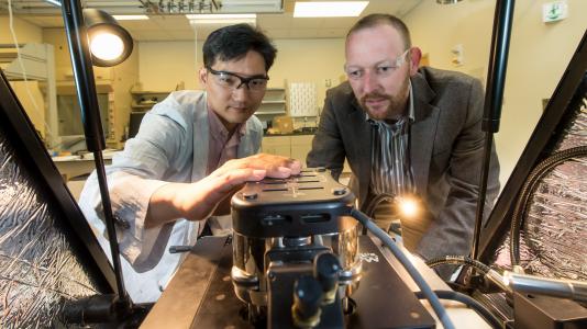 Argonne materials scientists Seungbum Hong (left) and Andreas Roelofs adjust an atomic force microscope.