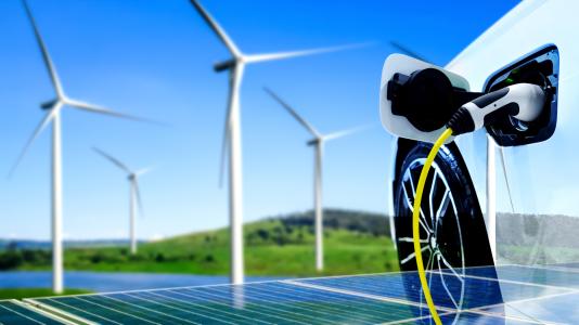Windmills, electric car, and solar panels with green landscape background