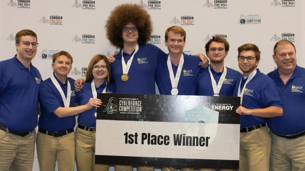 A team of college students wearing first place medals and holding a sign that says, "First place winner."