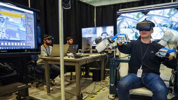 Man in a virtual reality headset in a room of computers and screens.